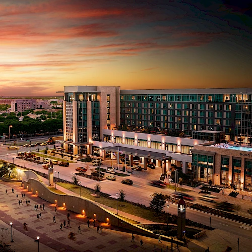 A modern city plaza with a large building, wide steps, and warm sunset skies casting a golden glow over the scene.