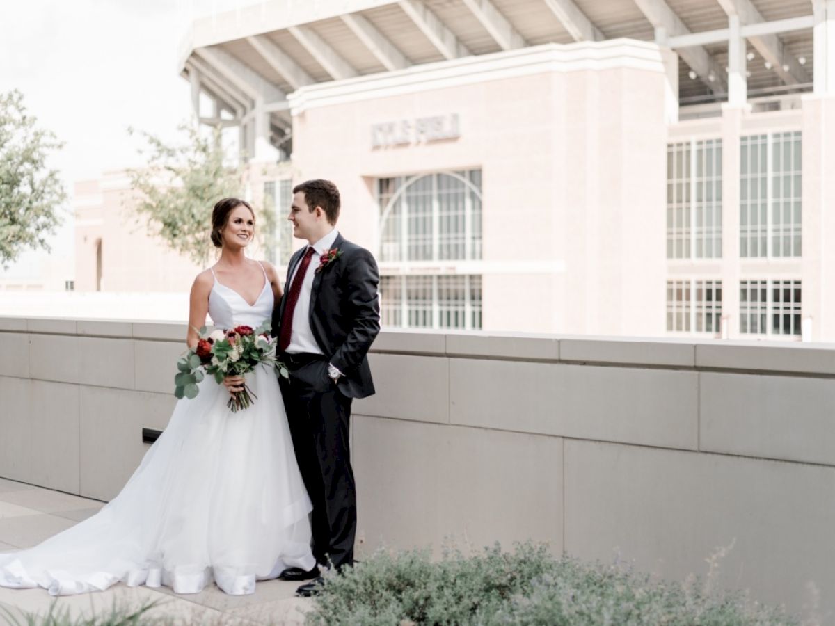 An Aggie bride and groom looking into each other's eyes with Kyle Field in the background