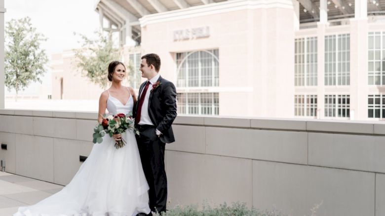 An Aggie bride and groom looking into each other's eyes with Kyle Field in the background