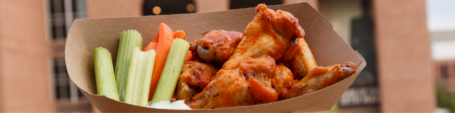 Takeout box with crunchy buffalo wings, celery sticks, and carrot sticks&mdash;feels like a spicy, crispy snack platter for sharing.