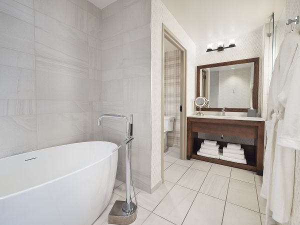 Modern, clean bathroom featuring a deep bathtub, sink, mirror, and toilet