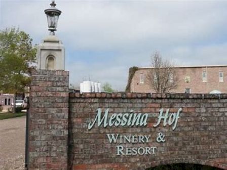 The image shows a brick wall with a sign for "Messina Hof Winery & Resort" in front of a brick building and a lamppost.