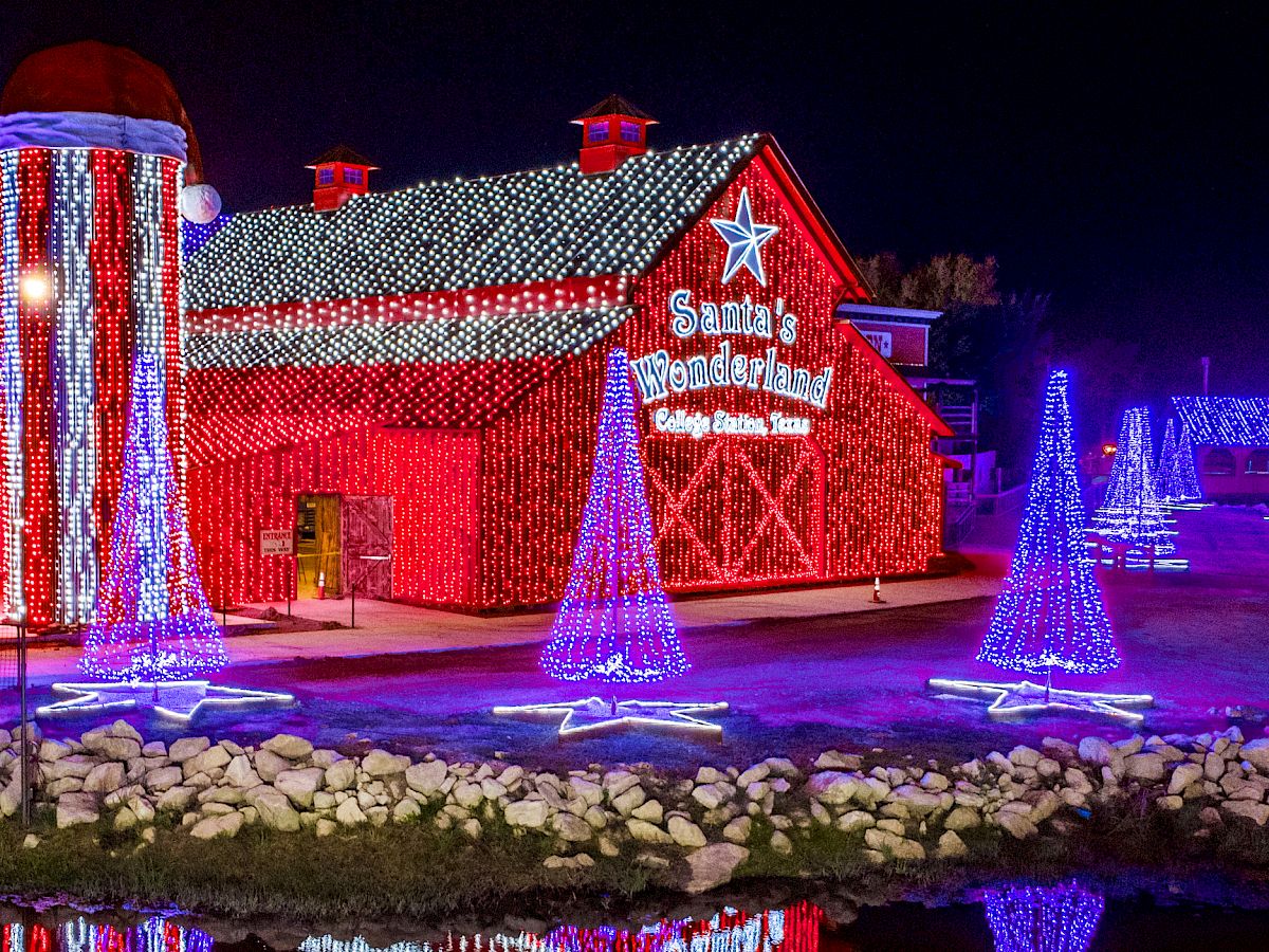 A festive light display shows Santa&rsquo;s Wonderland barn with &ldquo;Santa&rsquo;s Wonderland&rdquo; signage, plus colorful twinkling decorations and a towering Santa figure.
