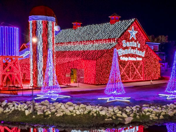 A bright Christmas light show at Santa&rsquo;s Wonderland, with lit barns, arches, and colorful LED decorations at night.