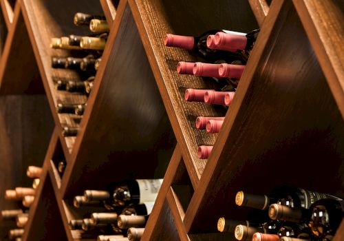 The image shows a wine rack with bottles of wine, arranged horizontally, and separated in diamond-shaped wooden compartments.