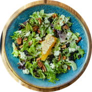 A bowl of fresh chopped green salad with avocado, herbs, and crunchy toppings.