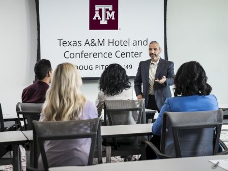 A speaker presents to a group at Texas A&M Hotel and Conference Center.