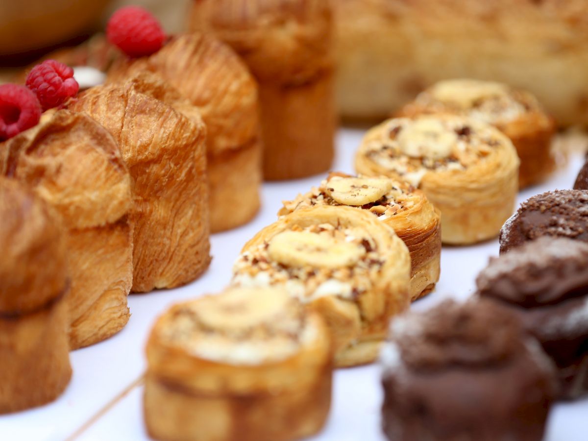Assorted pastries and bites arranged on a tray, including cream puffs, swirled rolls, and chocolate confections, all neatly lined up.