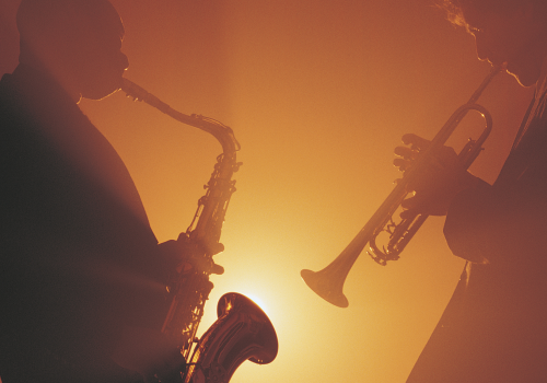 Two musicians silhouetted against a warm light, playing a saxophone and a trumpet, creating a harmonious scene.