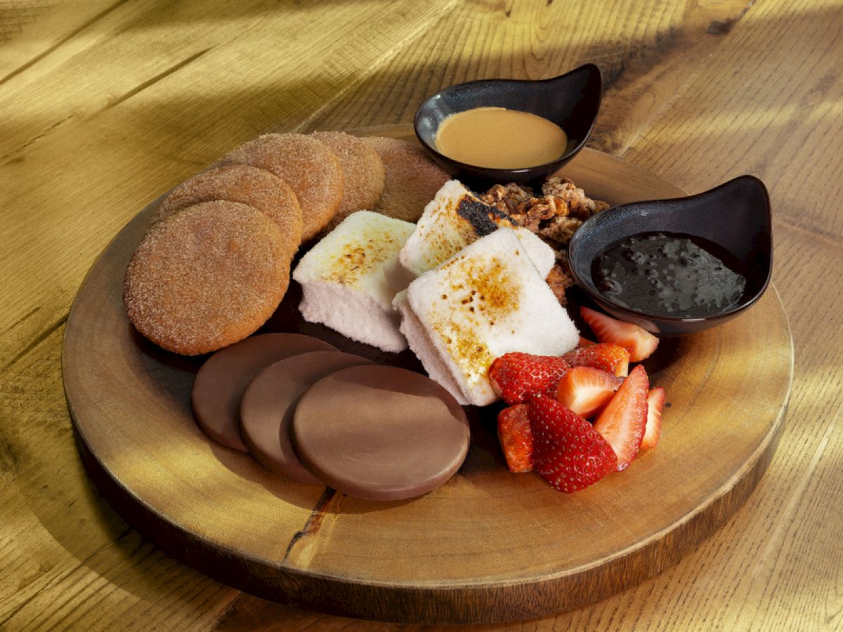 A wooden plate with a small assortment of chocolates and cookies, including dark and white chocolate pieces and a few fruit-flavored bits.