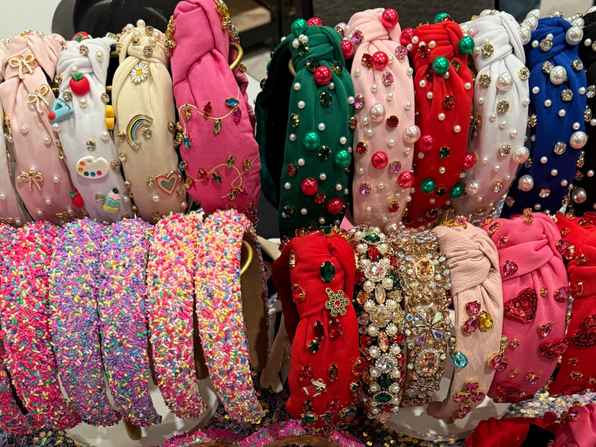 A display of colorful headbands with embellishments like pearls, beads, and embroidered designs arranged in two rows for sale.