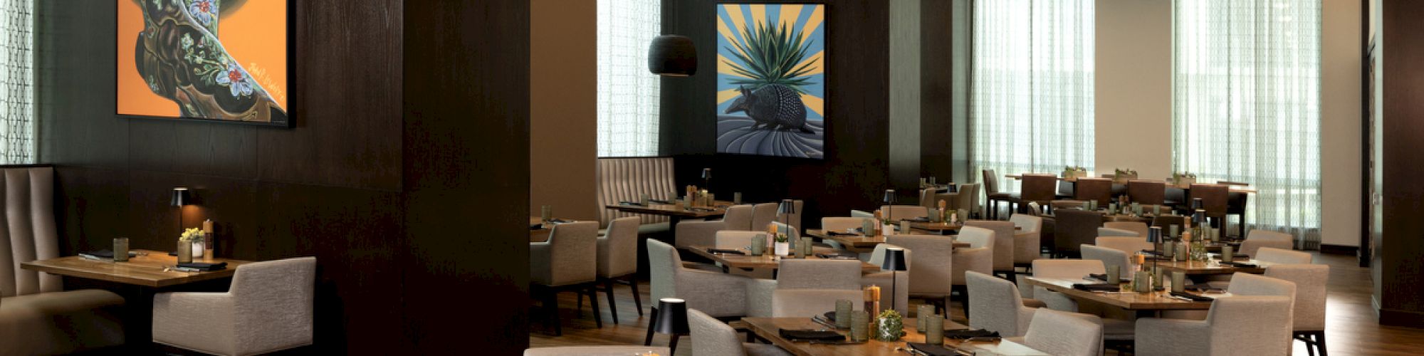 A modern restaurant interior with neatly arranged tables, abstract art on the walls, and a warm ambiance.